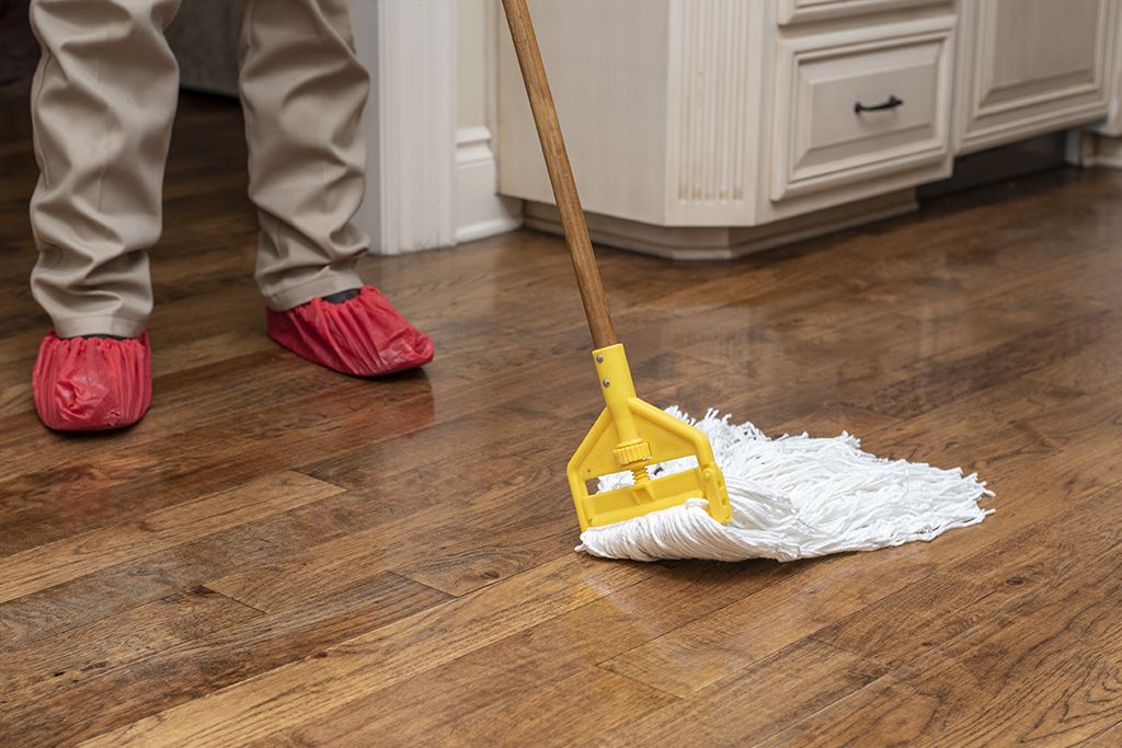 Employee cleaning a wooden floor with mop.
