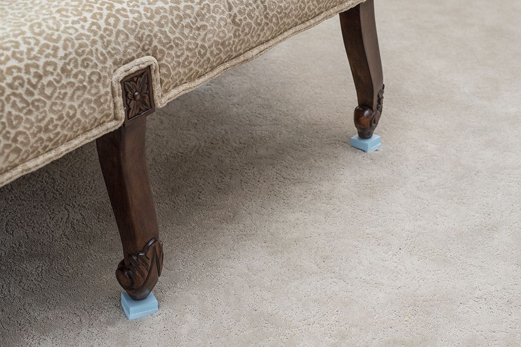 A sofa placed on block tabs to keep it from getting wet or transferring spots to professionally cleaned carpets as they dry