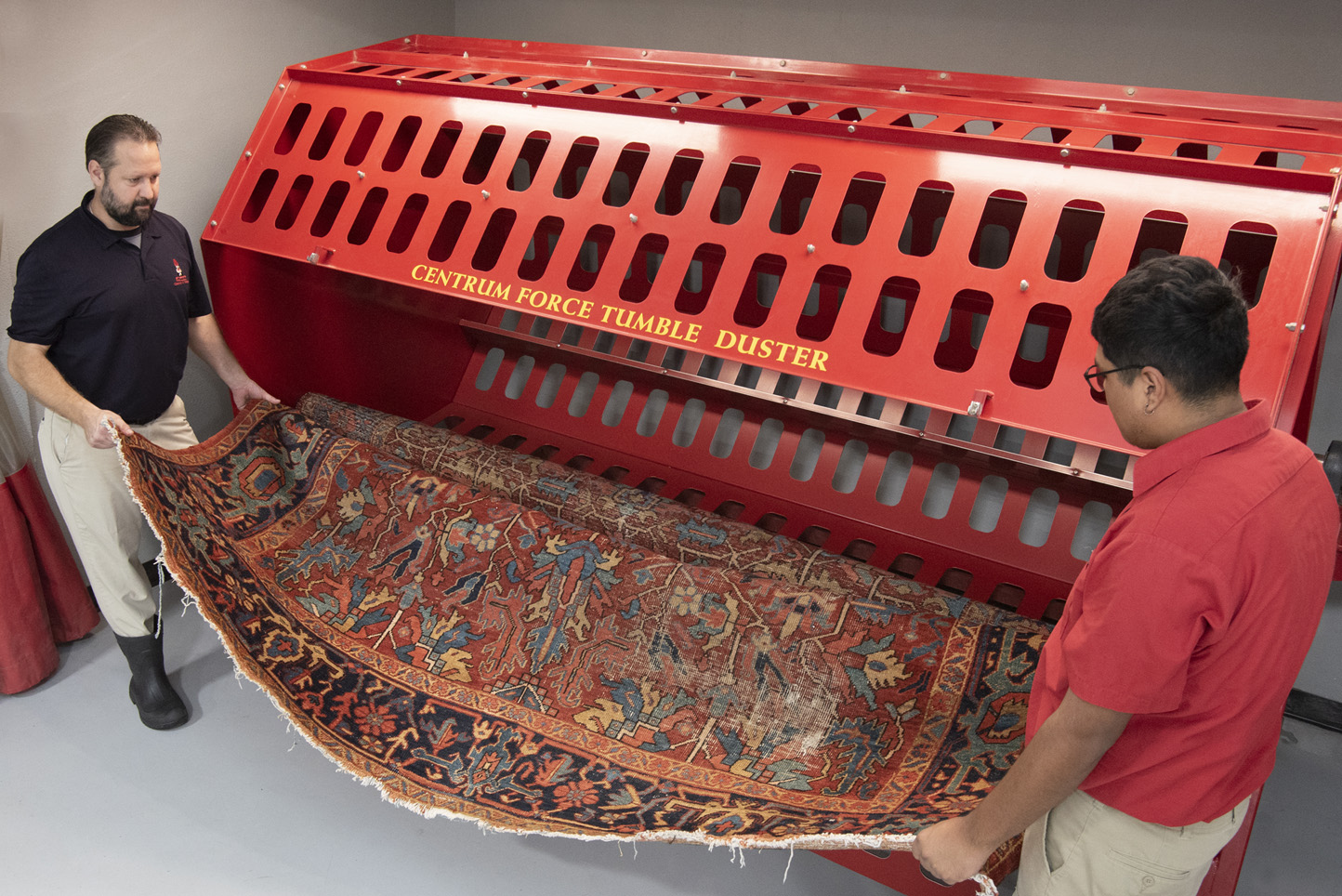 Aladdin Employee putting a rug through industrial machine to remove dry soil.