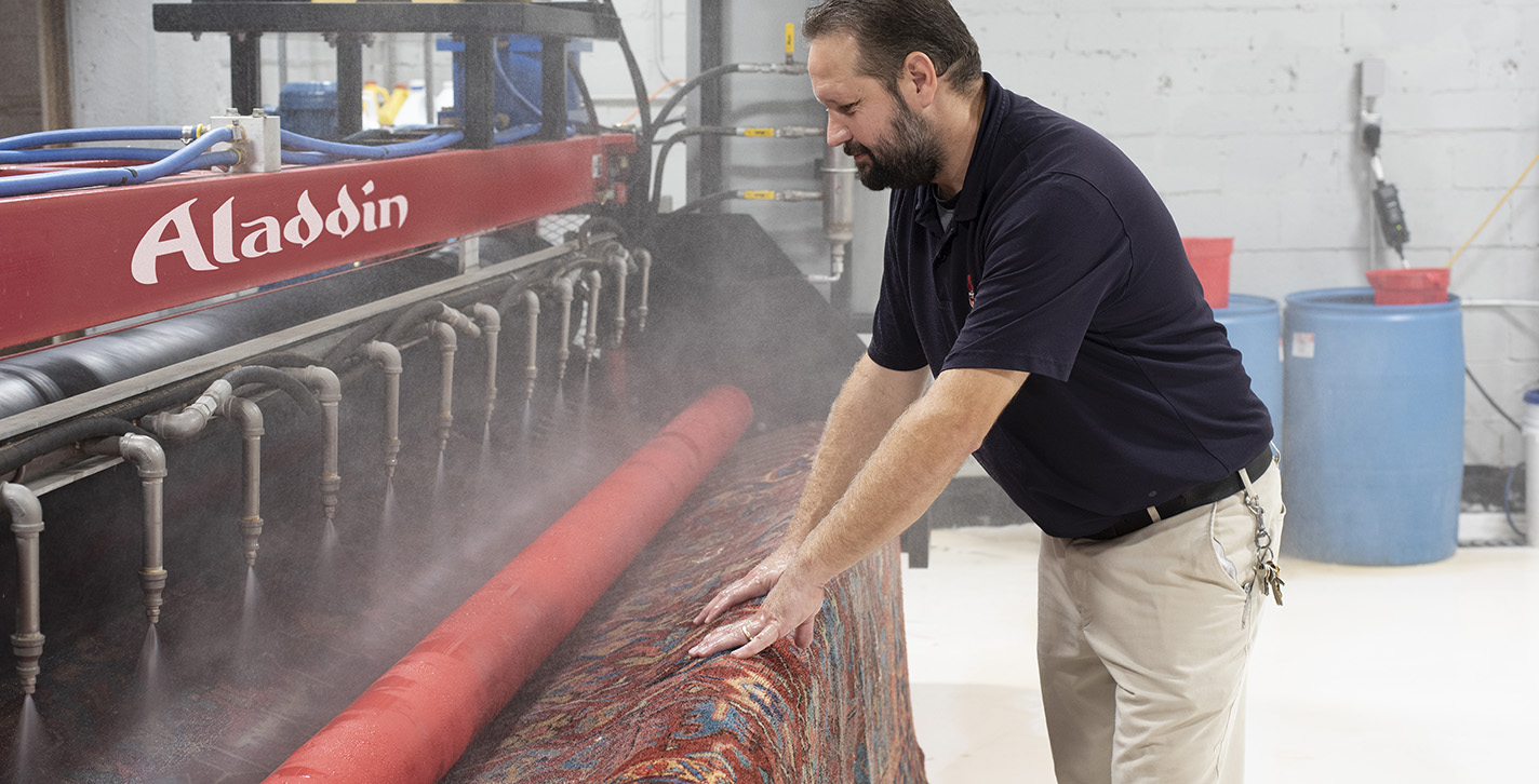 Aladdin cleaning specialist places antique, oriental rug into professional-grade rinse and wringer to remove dirt and debris