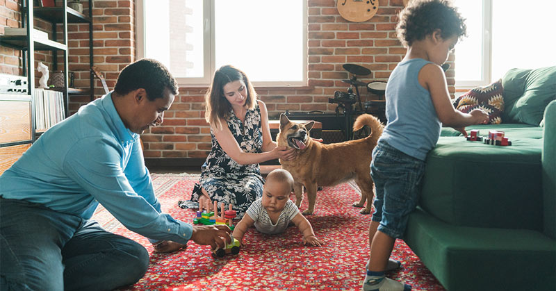 A red oriental rug in a living room with a family playing together